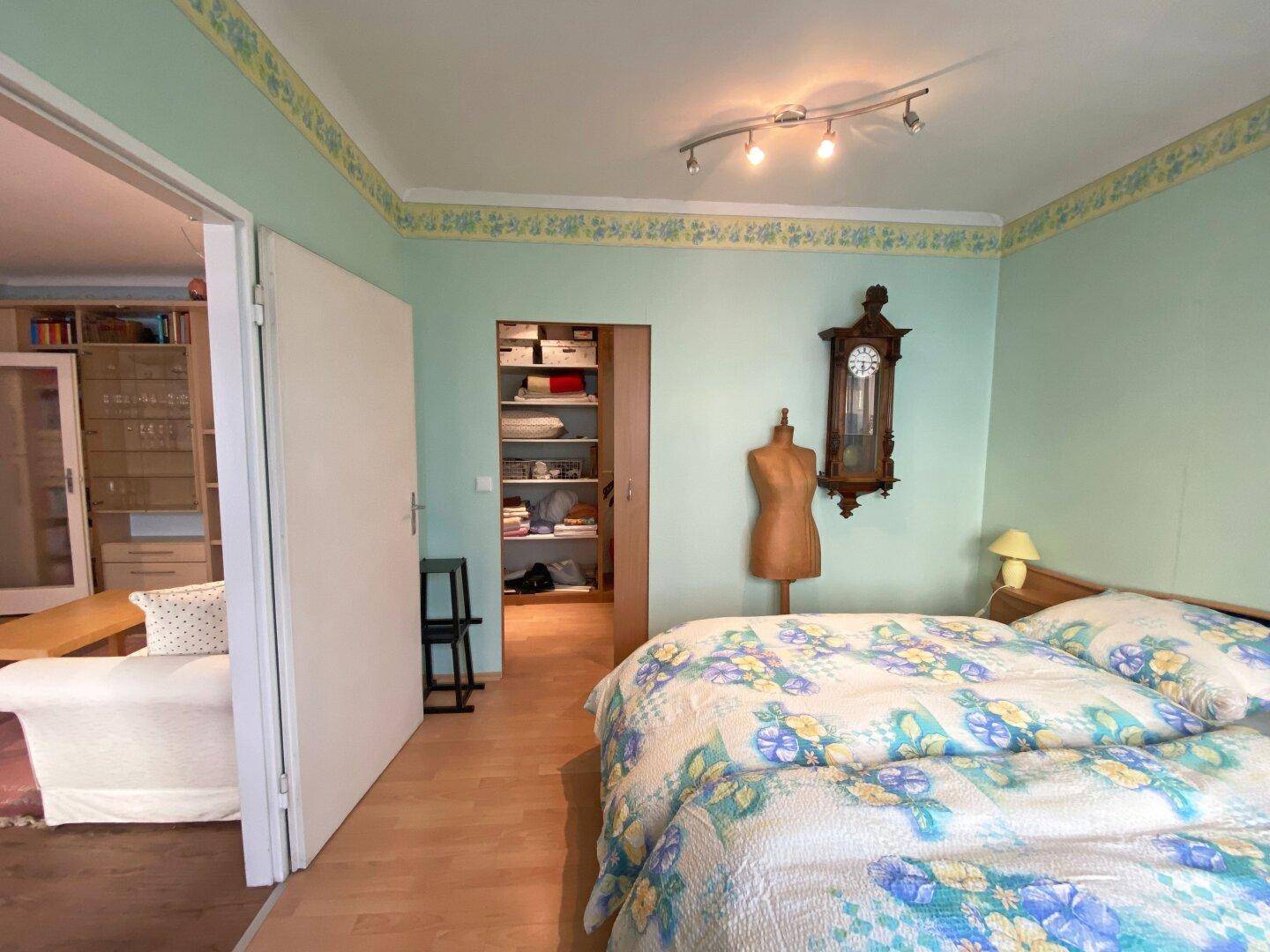 Schlafzimmer mit Doppelbett und Zugang zu einem begehbaren Kleiderschrank oder Abstellraum.
