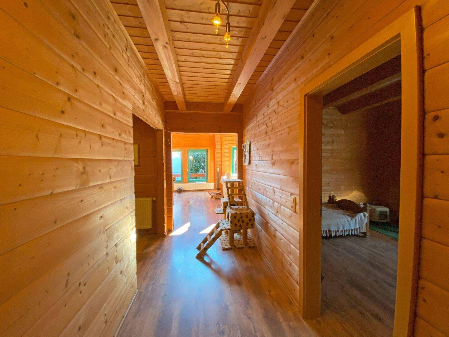 Gemütlicher Flur mit Holzwänden und Holzbalkendecke, der zu weiteren Räumen führt.