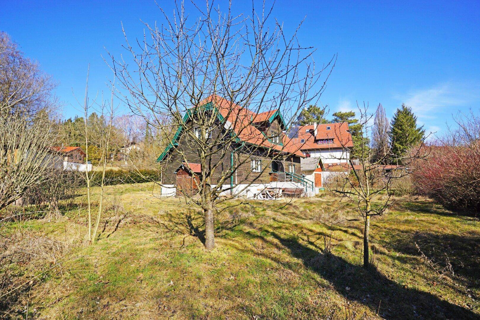 Charmantes Landhaus mit rotem Dach und grünen Akzenten, eingebettet in eine natürliche Umgebung.