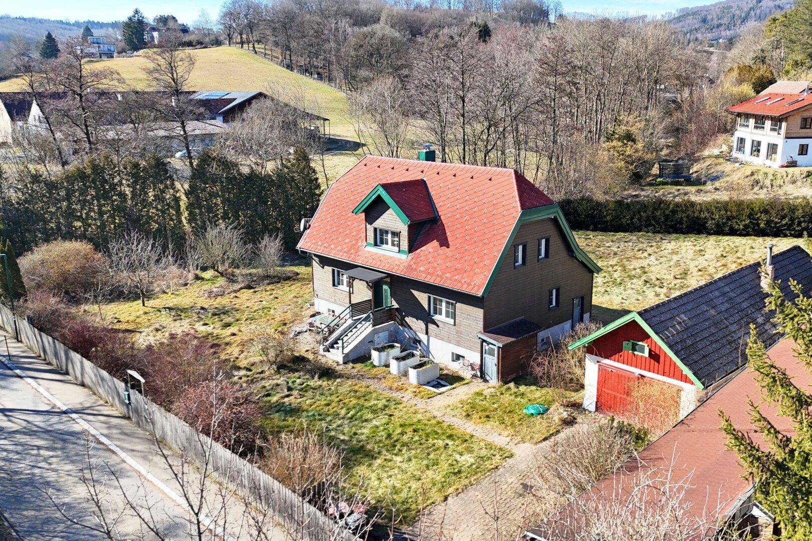 Luftaufnahme des Anwesens mit Haupthaus, Nebengebäude und angrenzender Zufahrtsstraße.