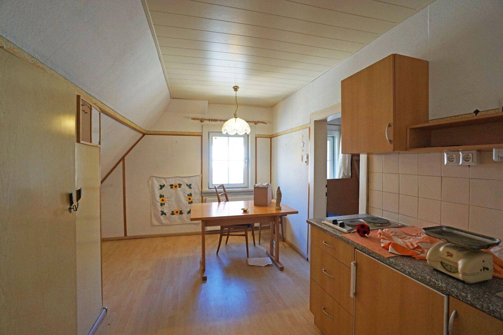 Einfache Küche mit Essbereich, Holzschränken und Dachschräge im Obergeschoss des Hauses.