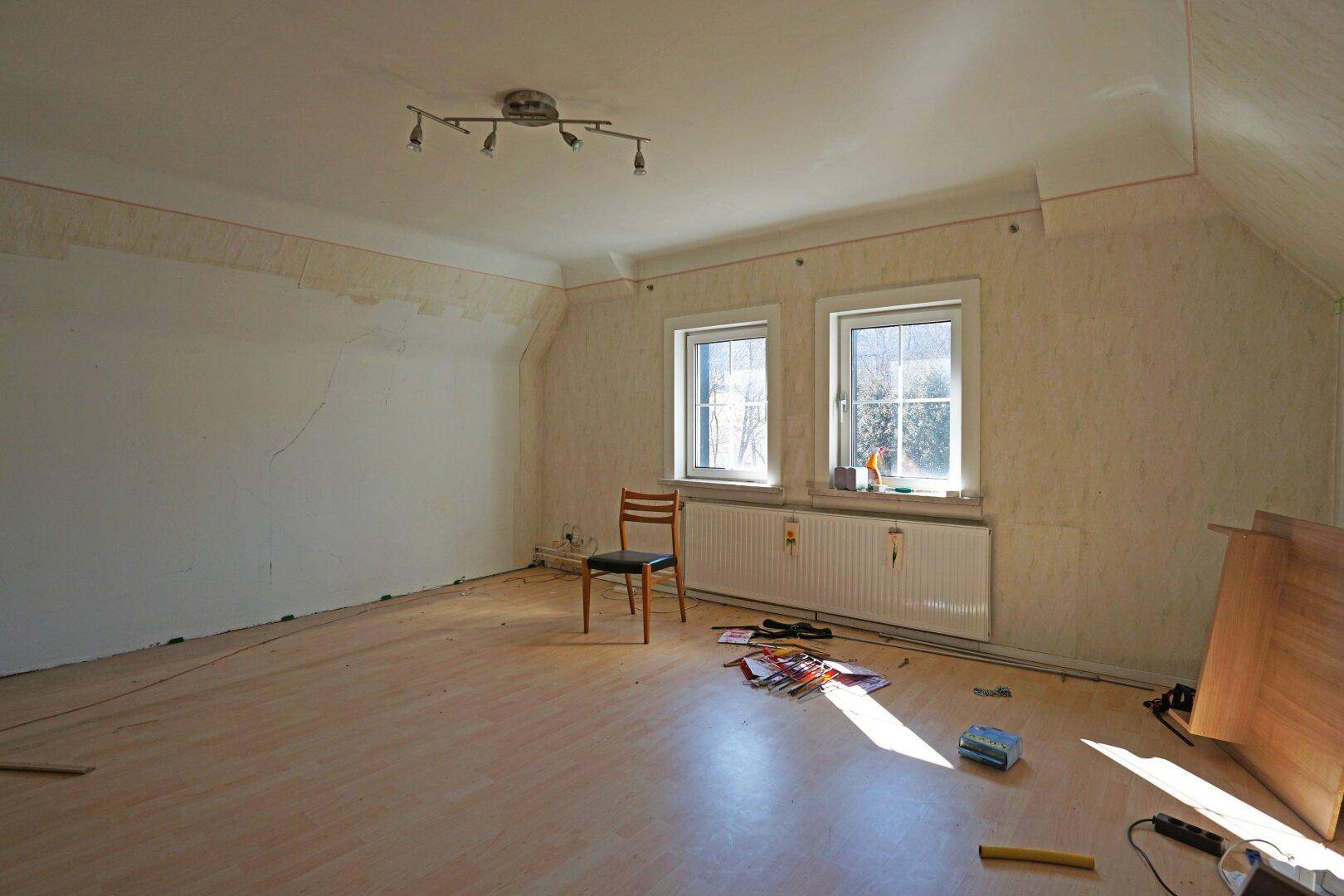 Geräumiges Schlafzimmer mit hellem Laminatboden und zwei Fenstern, bereit zur individuellen Gestaltung.