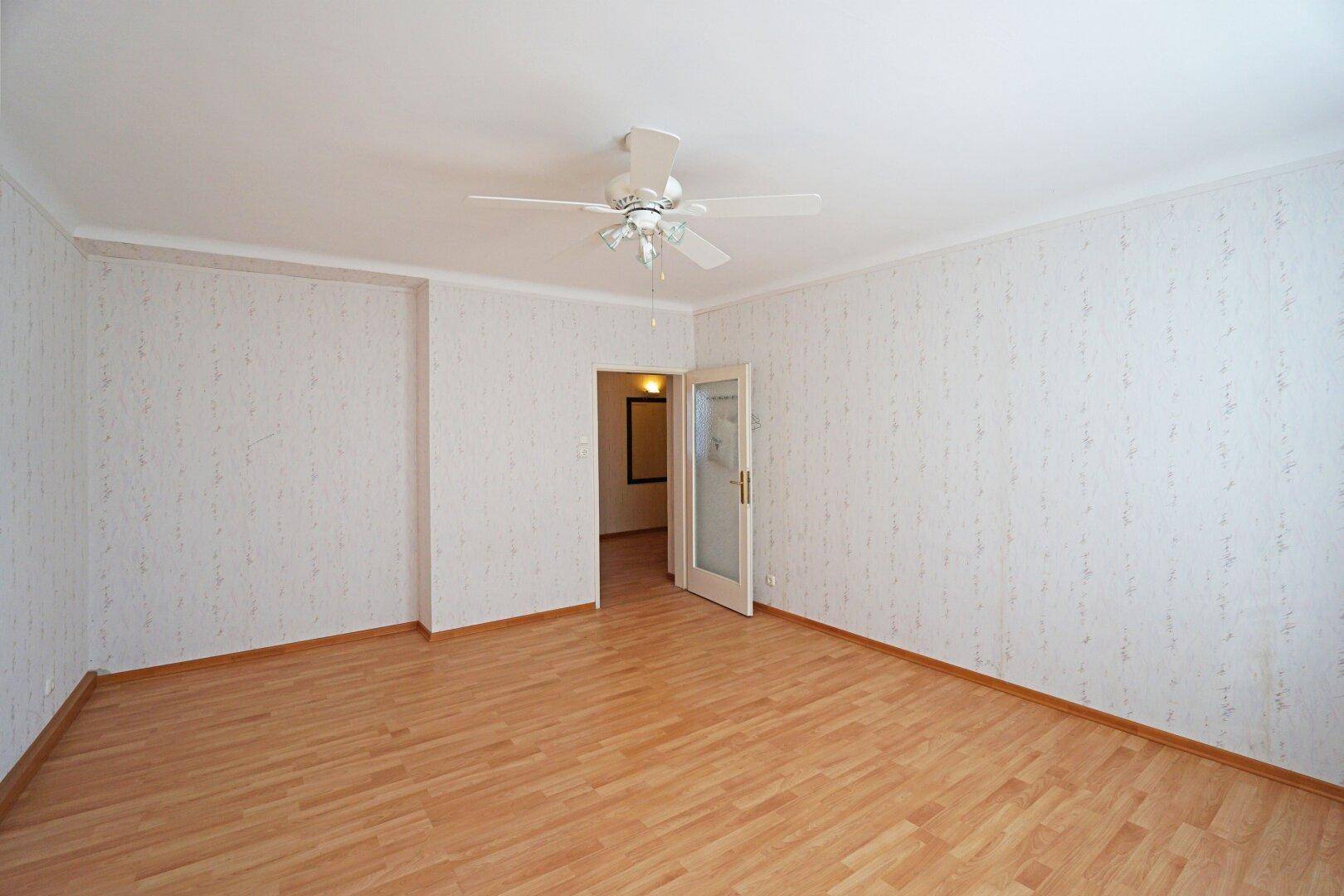 Geräumiges Zimmer mit Laminatboden und Deckenventilator, bereit für individuelle Einrichtung.