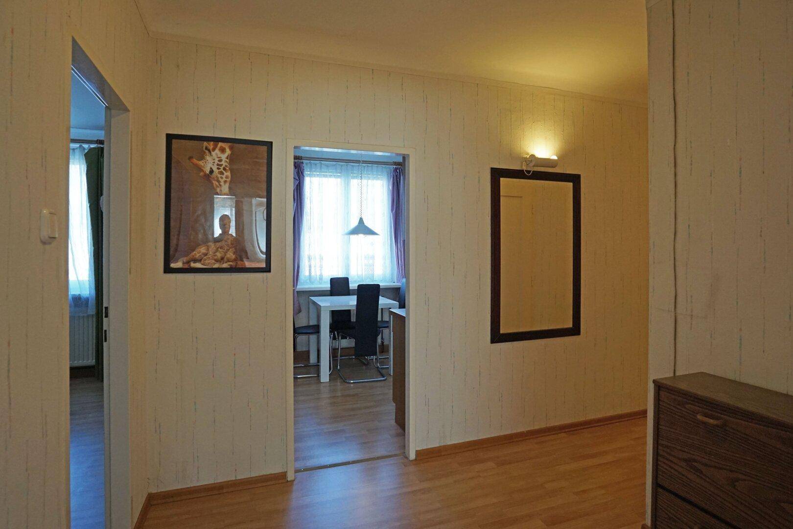 Flur mit Laminatboden und Zugang zu einem Essbereich mit Fenster.