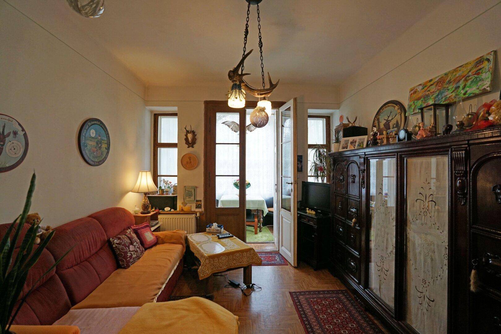 Gemütliches Wohnzimmer mit traditionellen Möbeln, Holzboden und Zugang zur Veranda.
