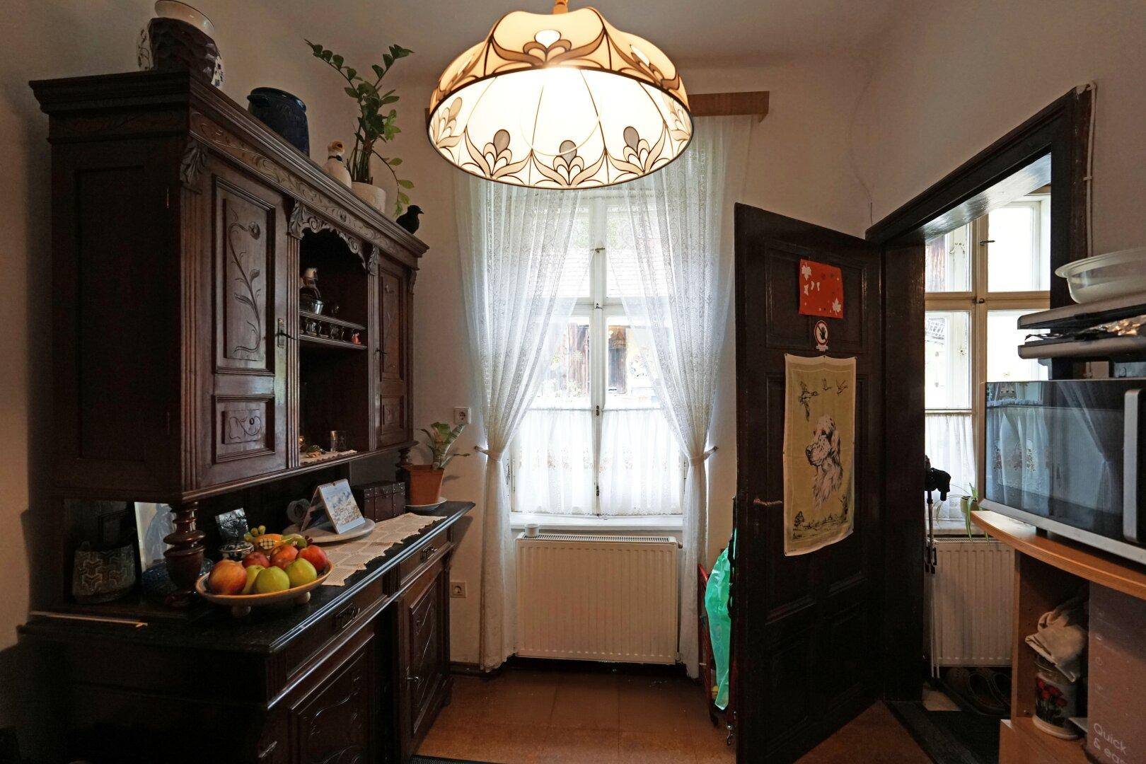 Raum mit einem großen, traditionellen Holzschrank, Fenster und einem dekorativen Licht.