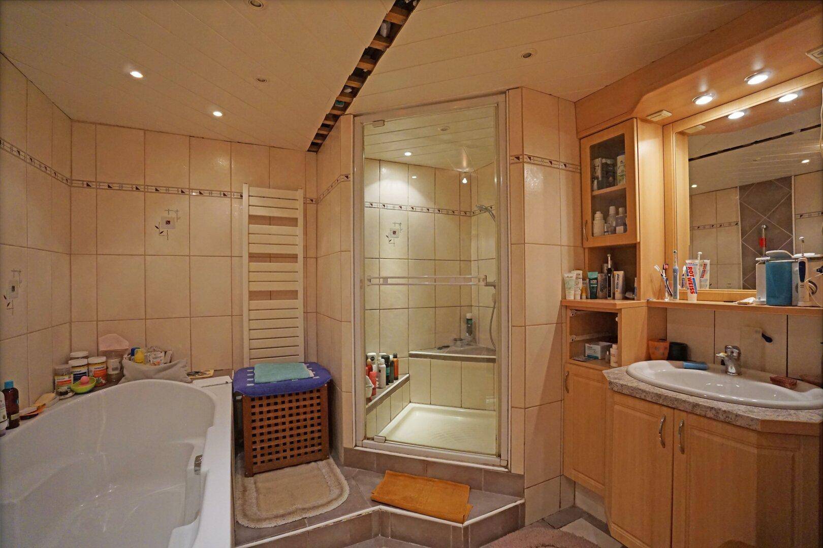 Helles Badezimmer mit Badewanne, Duschkabine, Waschbecken und Fliesen an den Wänden.