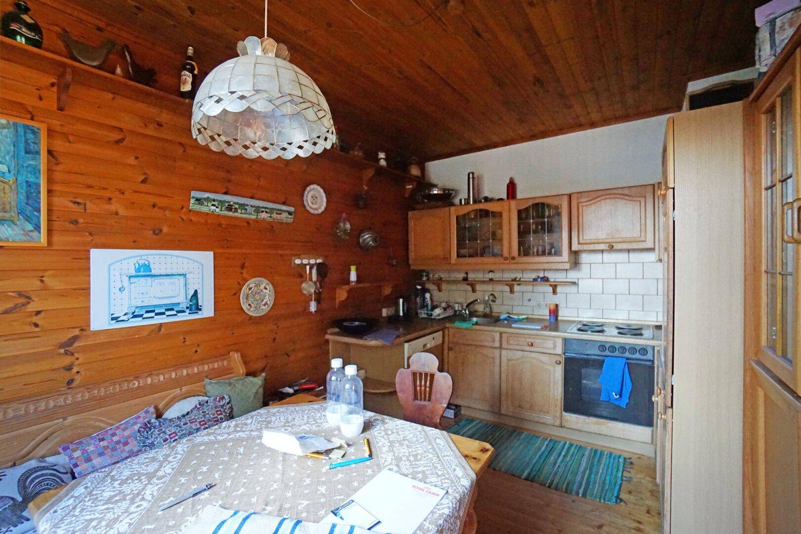 Kleine Küche im Landhausstil mit Holzschränken, Spüle und Kochfeld, integriert in den Essbereich.