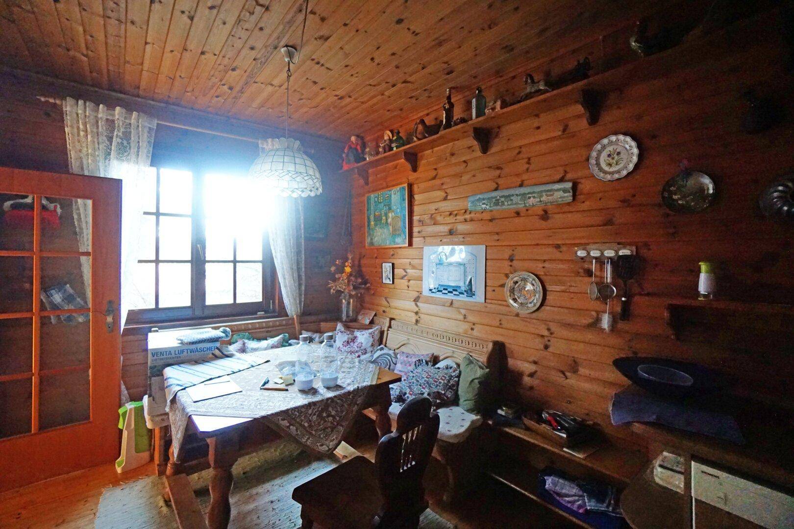 Gemütlicher Wohn-Essbereich mit Holztäfelung, Esstisch und dekorativen Wandregalen.