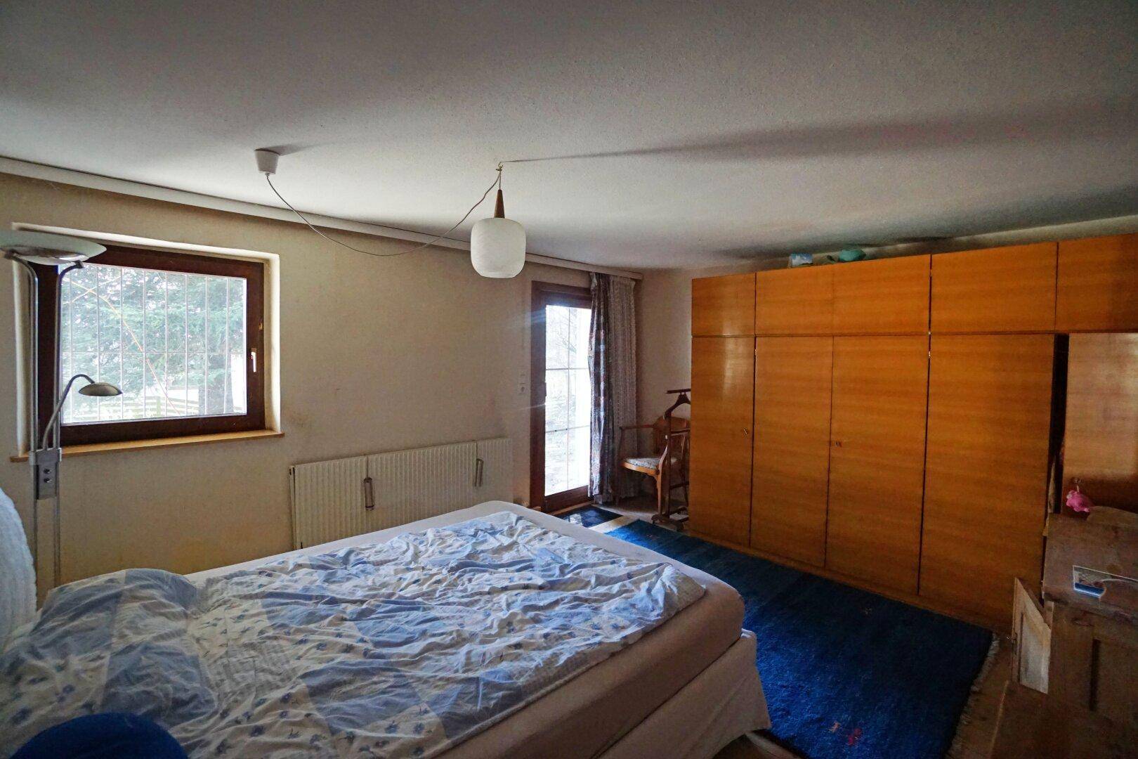 Schlafzimmer mit großem Kleiderschrank, Bett und Zugang zu einem Balkon oder Terrasse.
