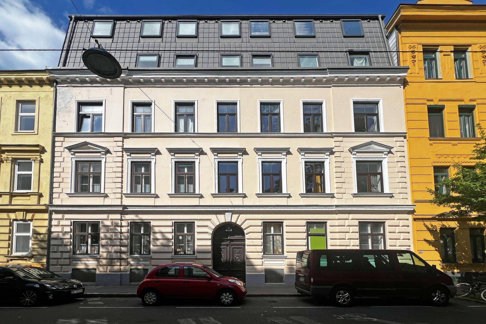 Historisches Gebäude mit einer modernisierten Dachgeschossfassade und vielen kleinen Fenstern an einer Straße.