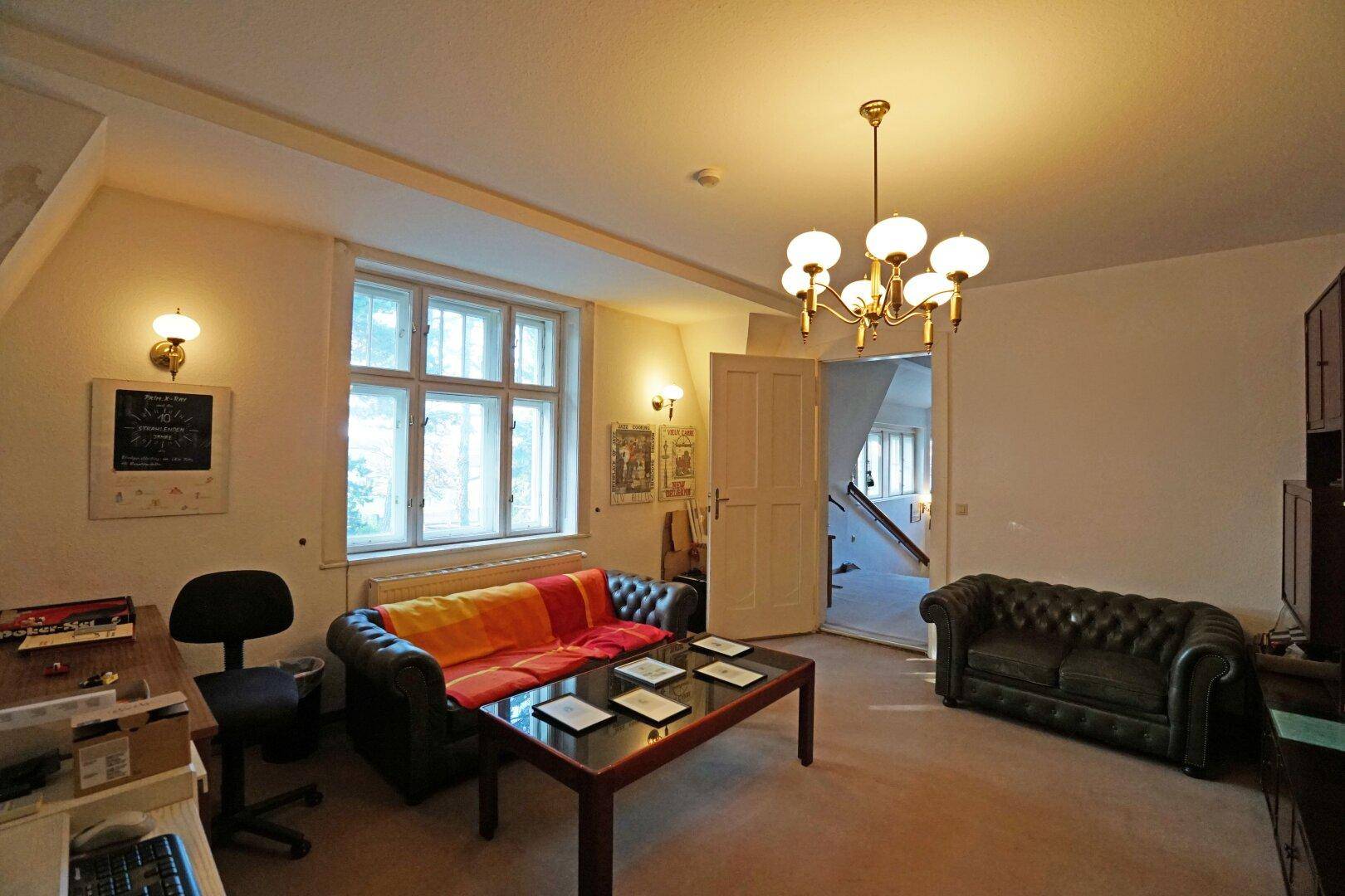 Gemütliches Wohnzimmer mit zwei Sofas, Teppichboden und Blick ins Grüne.