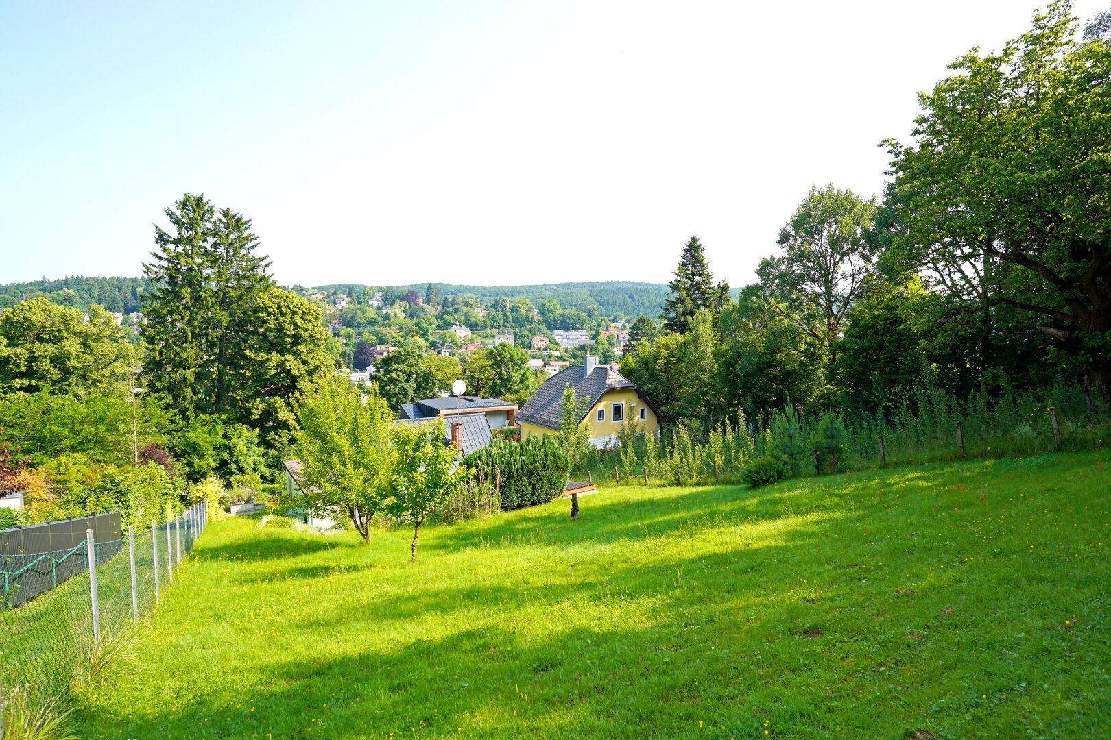 Große grüne Rasenfläche mit Blick auf die umliegende Landschaft und Häuser in der Ferne.