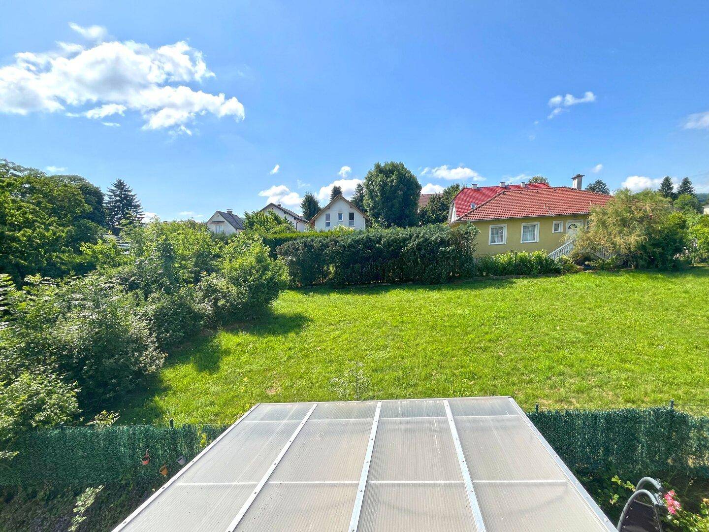 Weitläufiger Blick über den grünen Garten und die umliegende Wohnsiedlung mit viel Natur.