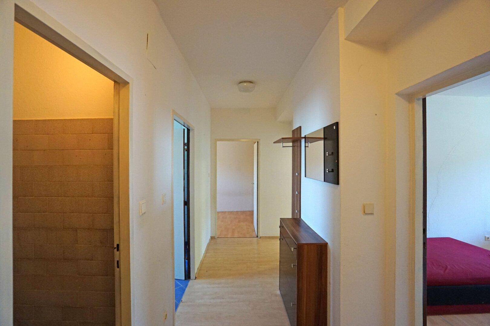 Heller Flur mit Holzfußboden, Garderobe und Zugang zu verschiedenen Zimmern.