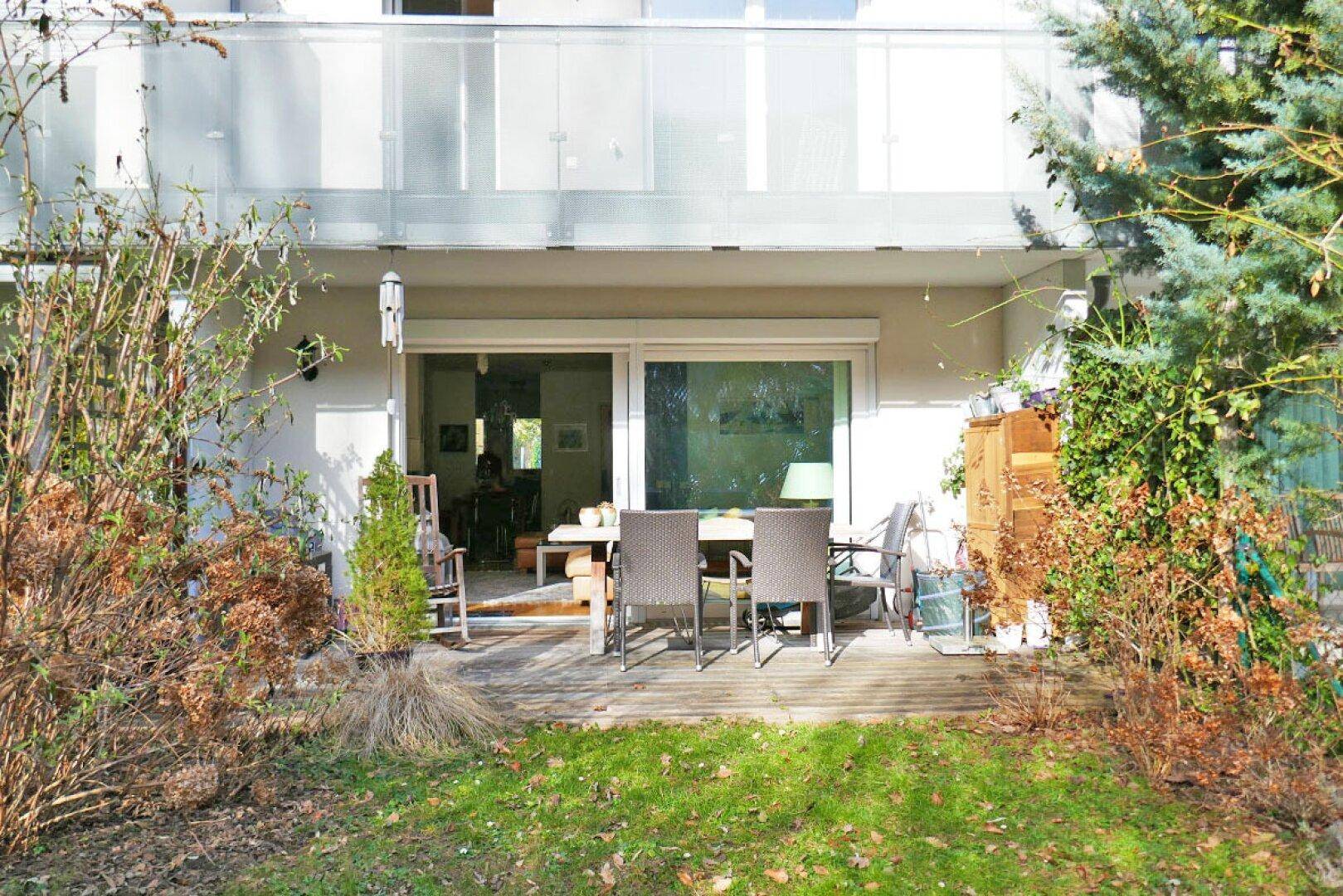 Sonniger Terrassenbereich mit Gartenmöbeln und direktem Zugang zum gepflegten Rasenbereich.