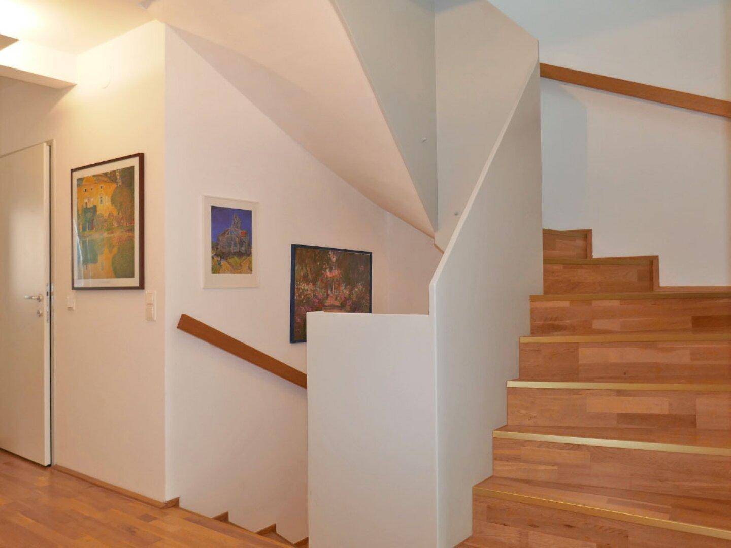 Modernes Treppenhaus mit Holzstufen und weiß gestrichenen Wänden, hell und offen gestaltet.