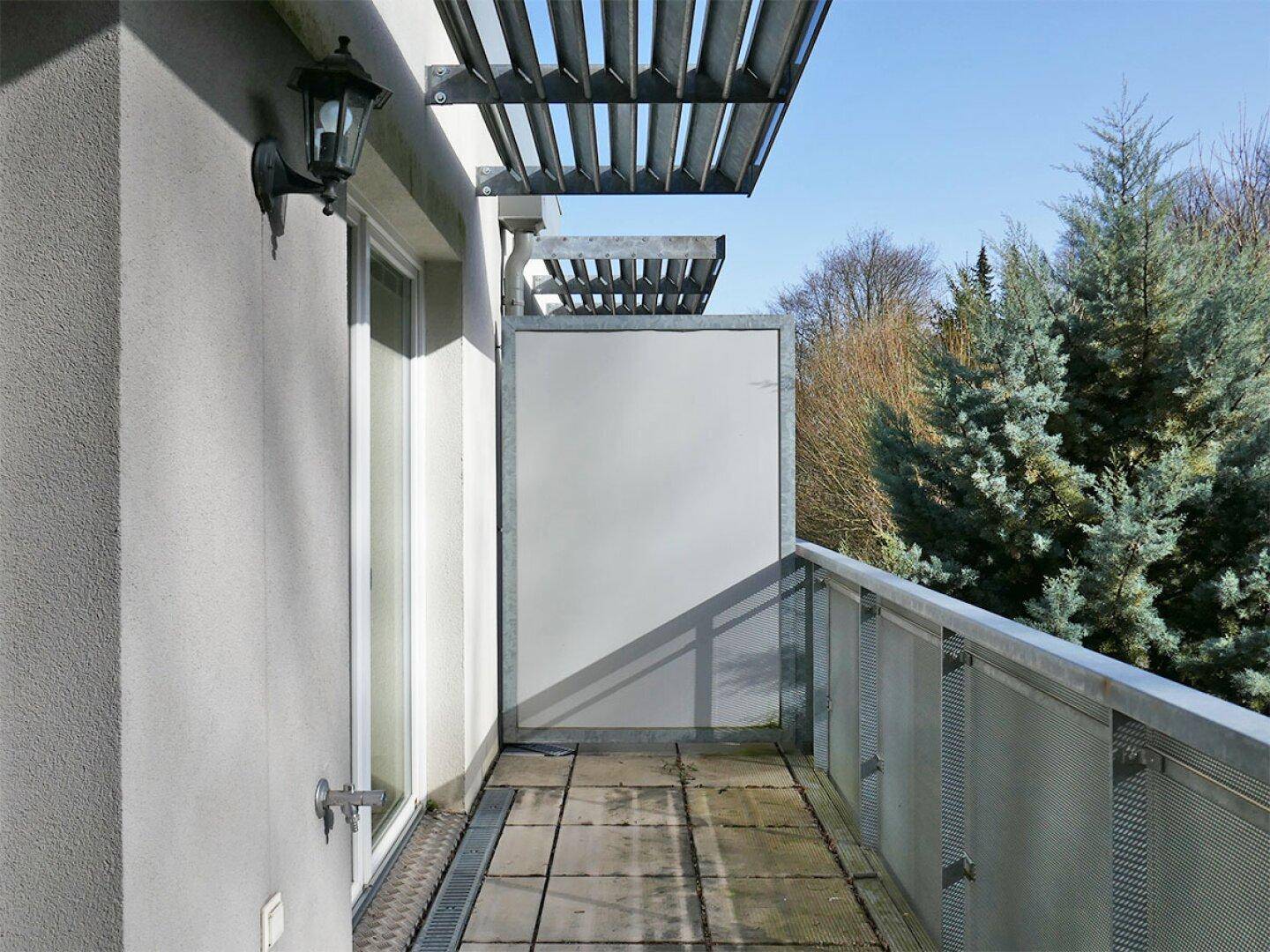 Kleiner Balkon mit Metallgeländer und Blick ins Grüne, ideal für eine kurze Auszeit.