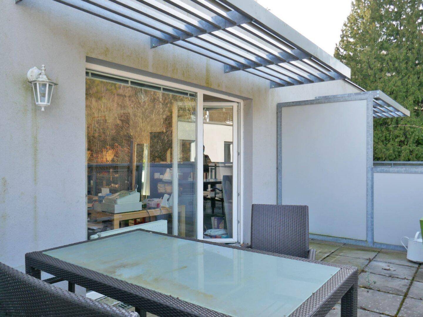 Obere Terrasse mit Sitzgelegenheiten und Blick auf die umliegende Natur und Bäume.