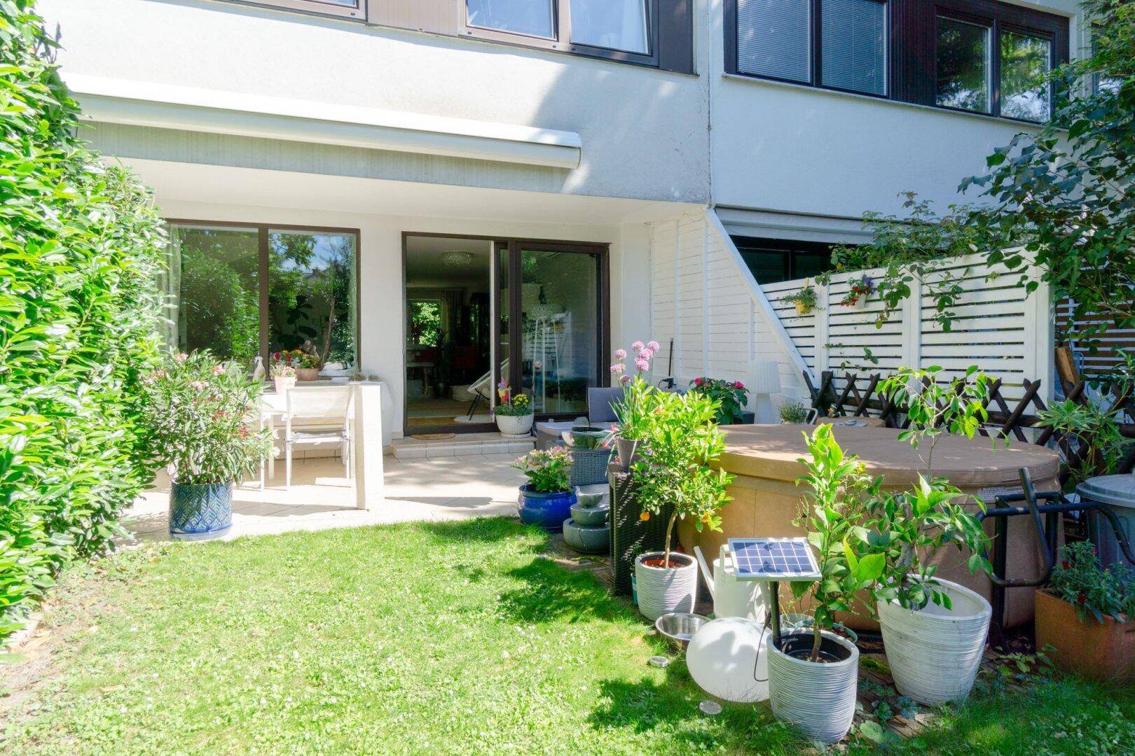 Gepflegter Gartenbereich mit Rasenfläche, Terrasse und Whirlpool, ideal zum Entspannen im Freien.