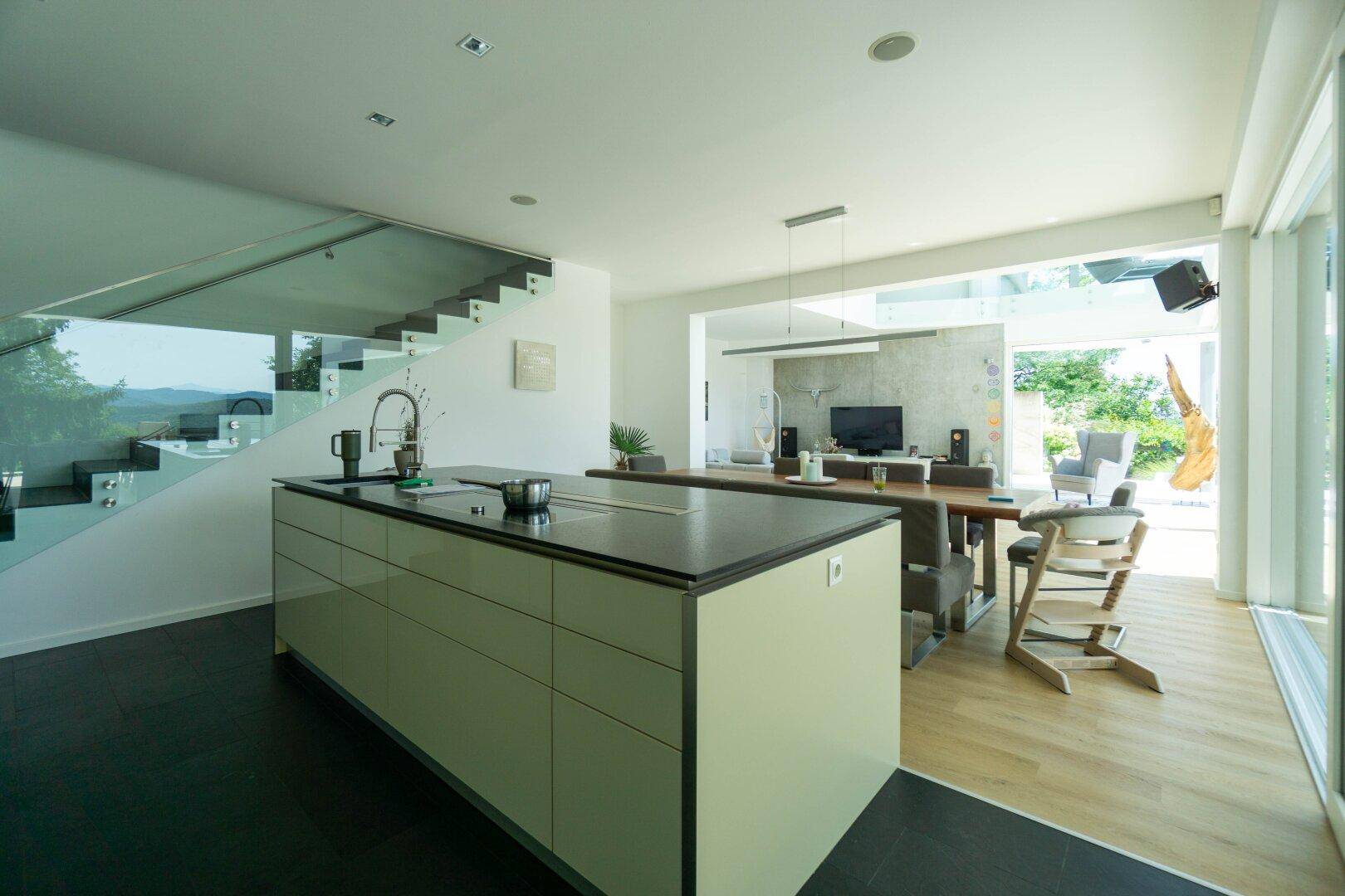 Moderne Küche mit Kochinsel, Essbereich und offenem Übergang zum Wohnzimmer mit Poolblick.