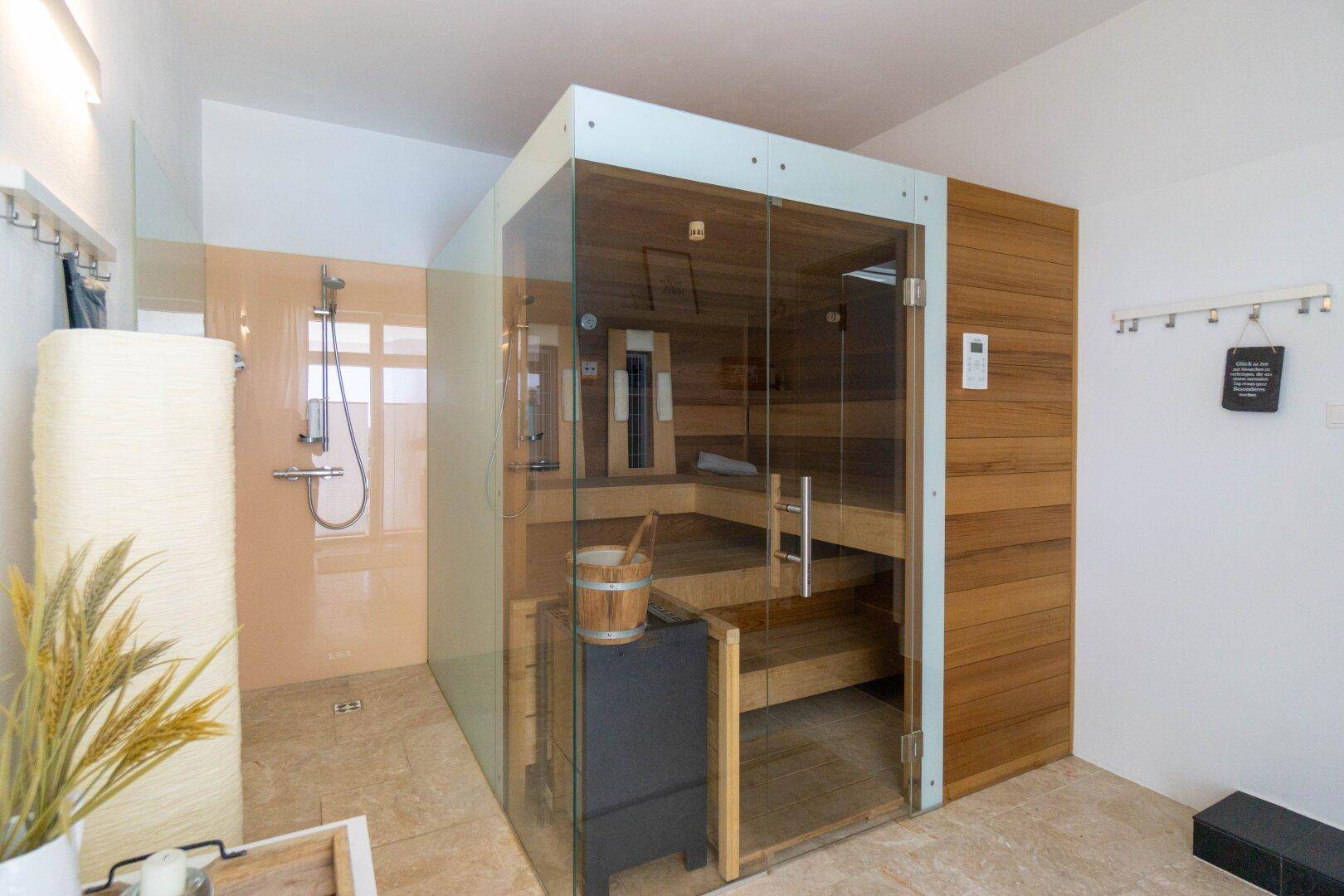 Modernes Badezimmer mit Sauna, begehbarer Dusche und Holzverkleidung für Wellnessmomente.