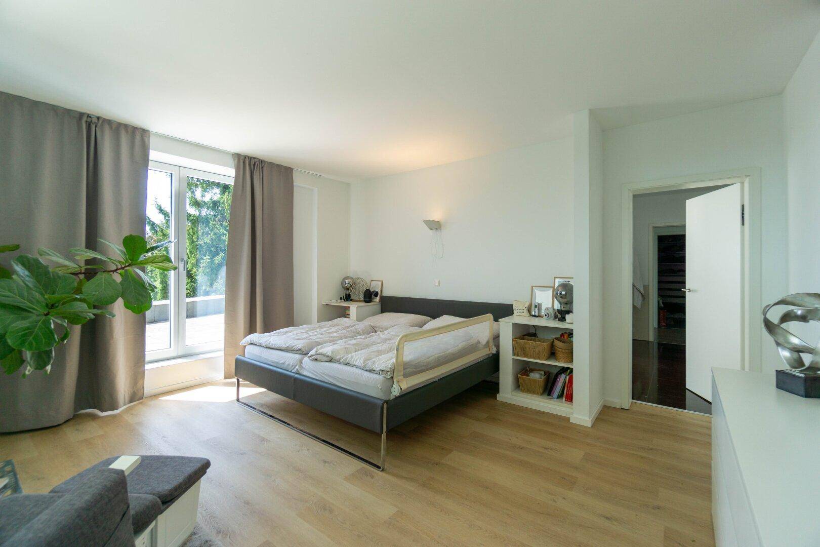 Helles Schlafzimmer mit Doppelbett, Holzboden und Zugang zu einer Terrasse mit Weitblick.