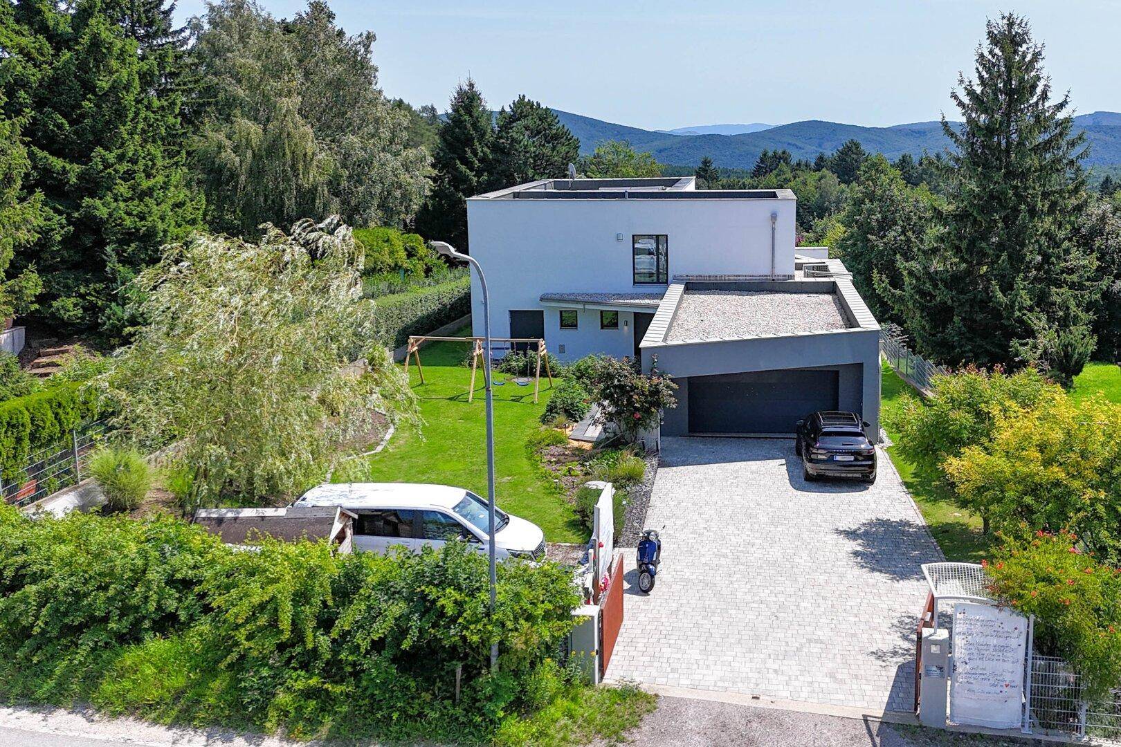 Ansicht der modernen Villa von der Zufahrt mit Doppelgarage und weitem Blick in die Landschaft.