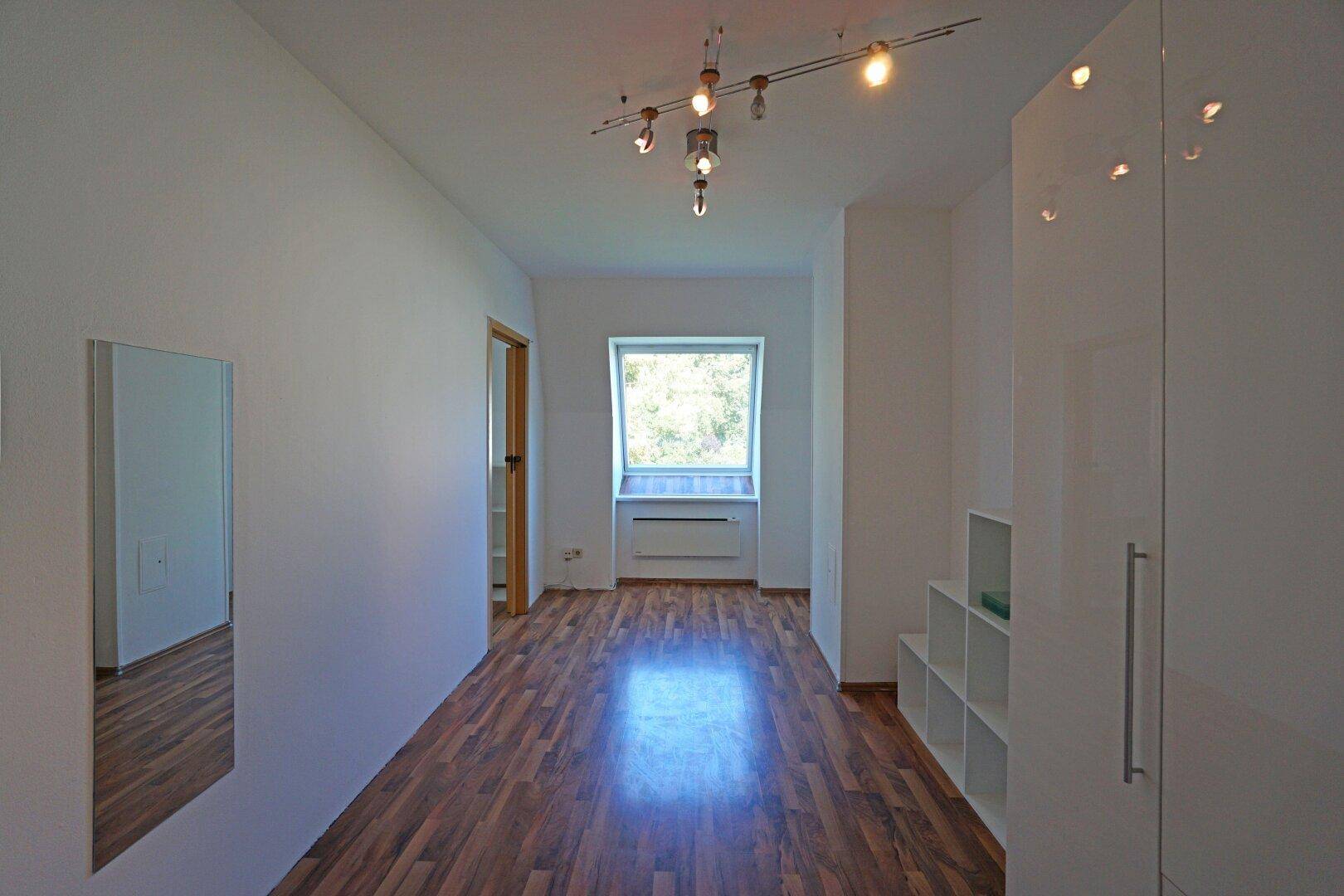 Heller Flur mit Laminatboden, weißem Einbauschrank und einem Dachfenster.