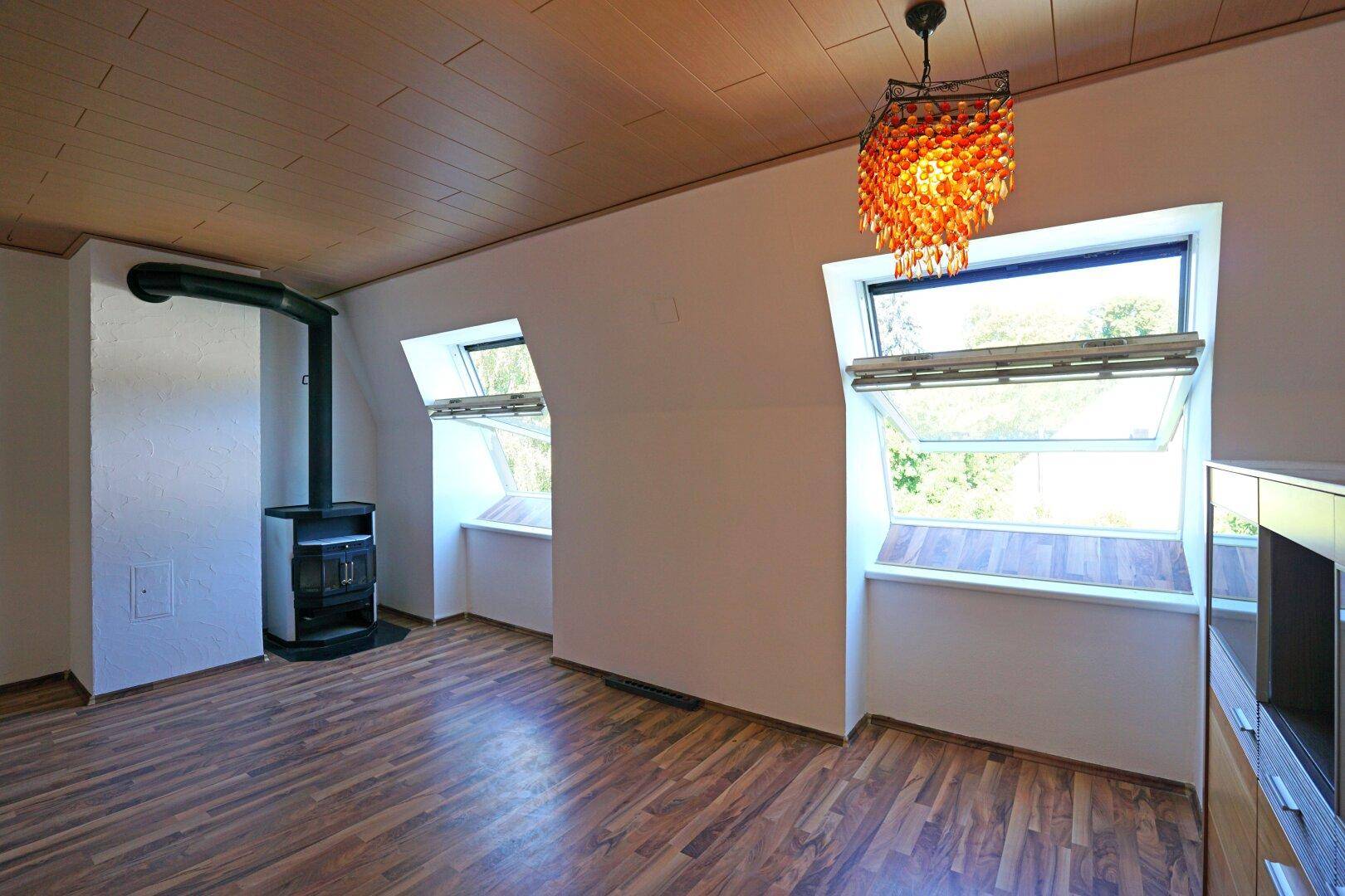 Gemütliches Wohnzimmer mit Kaminofen, Laminatboden und Dachfenstern für viel Licht.