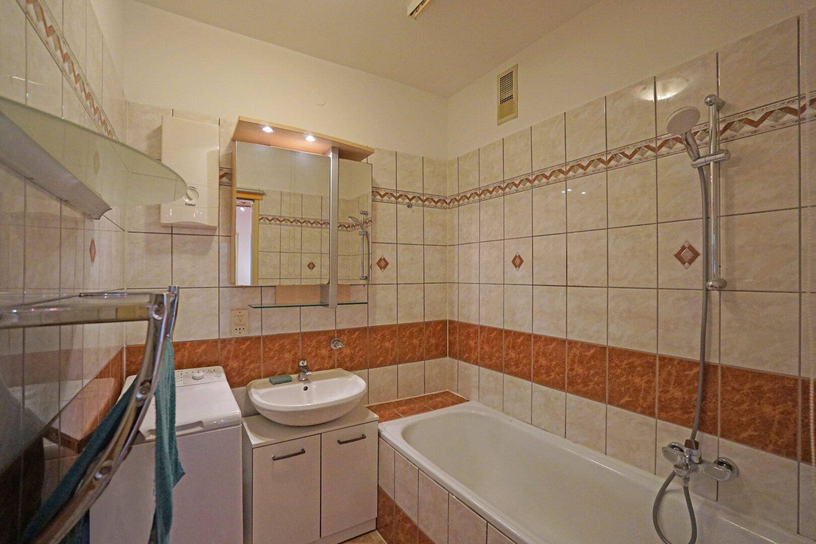 Gefliestes Badezimmer mit Badewanne, Waschbecken und einem Spiegelschrank.