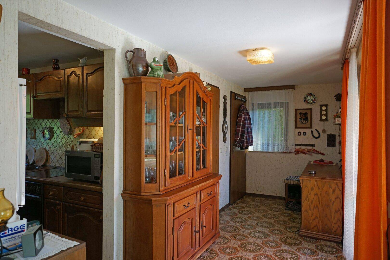 Gemütlicher Flur mit traditionellen Holzmöbeln und Blick in eine angrenzende Küche.