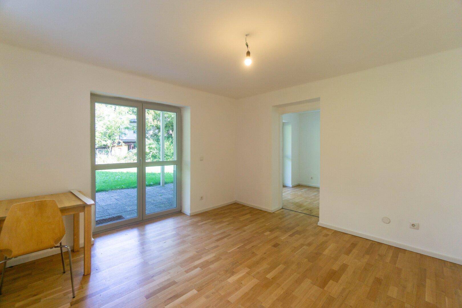 Erdgeschosszimmer mit Parkettboden und direktem Zugang zum Garten, hell und einladend.