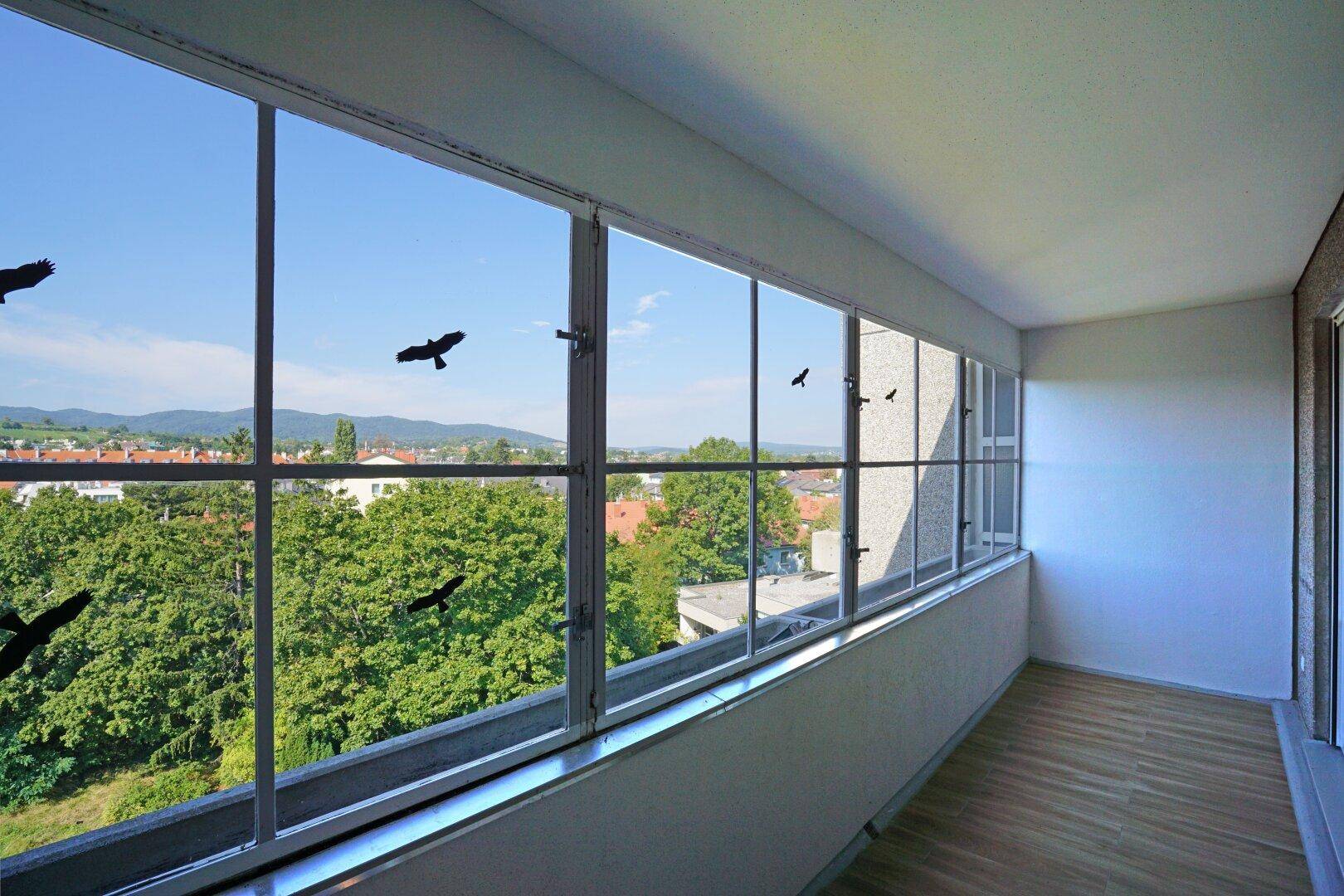 Verglaste Loggia mit weitem Blick ins Grüne und auf die umliegende Stadtlandschaft.