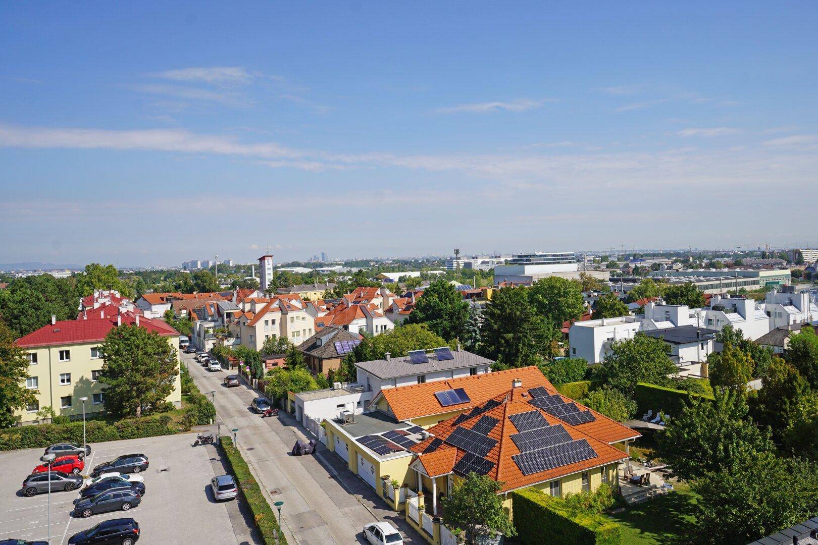 Weitläufiger Blick über die Stadt mit Wohngebäuden, Solaranlagen und viel Grün.