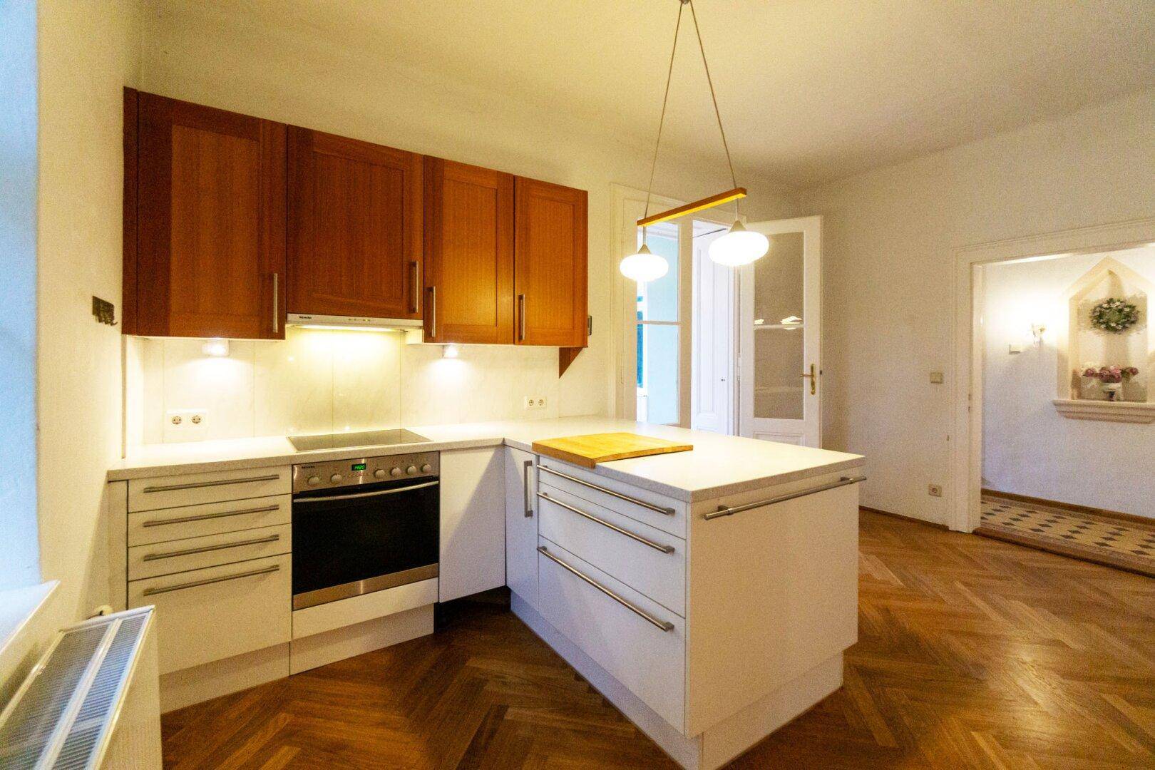 Moderne Küche mit Holzakzenten, Kochfeld und praktischer Kücheninsel.
