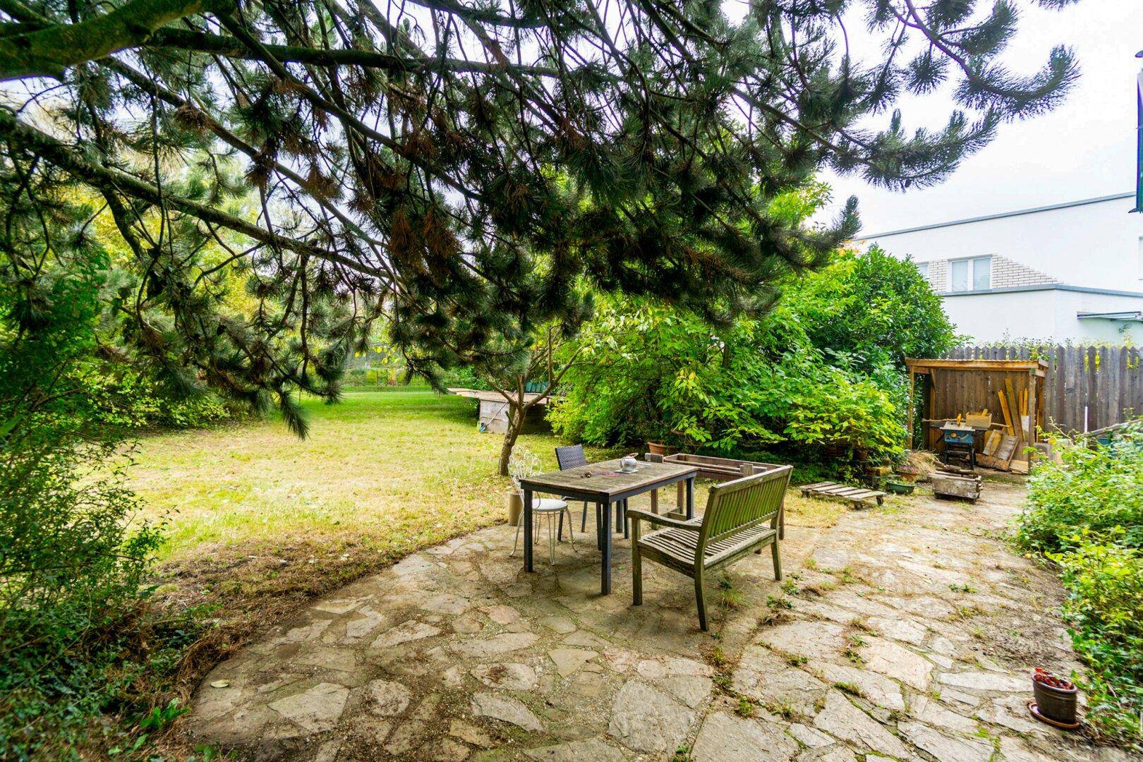 Großer, gepflegter Garten mit Rasenfläche, Sitzbereich und altem Baumbestand.