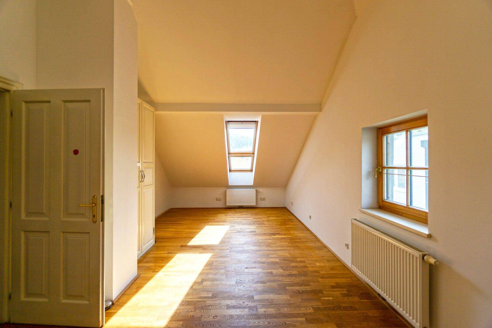 Helles Dachzimmer mit Holzboden, Dachfenster und viel natürlichem Licht.
