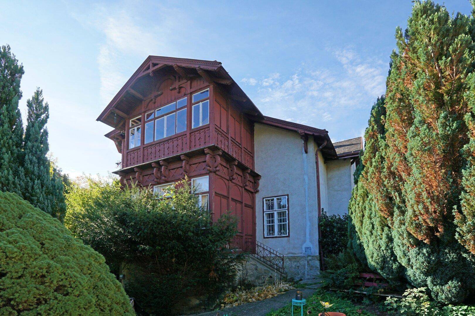 Detailansicht der historischen Villa mit charakteristischer Holzverkleidung und großen Fenstern.