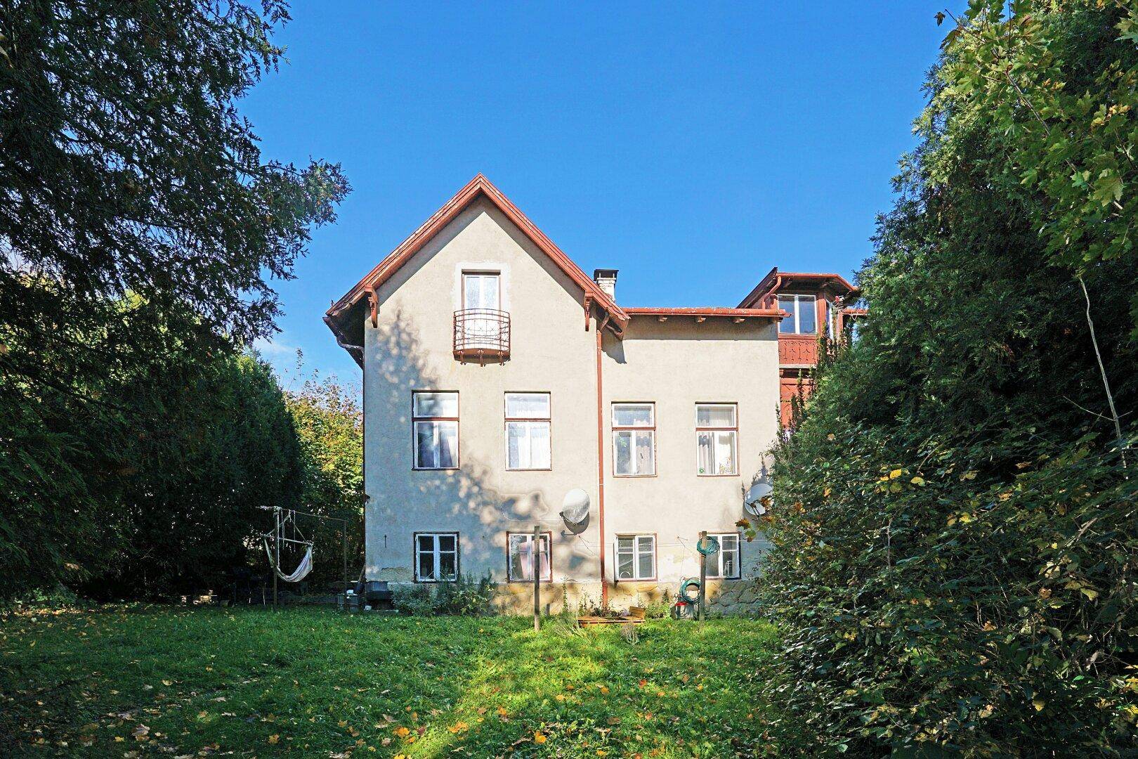Rückansicht der Villa mit kleinem Balkon und Blick auf den weitläufigen Garten.