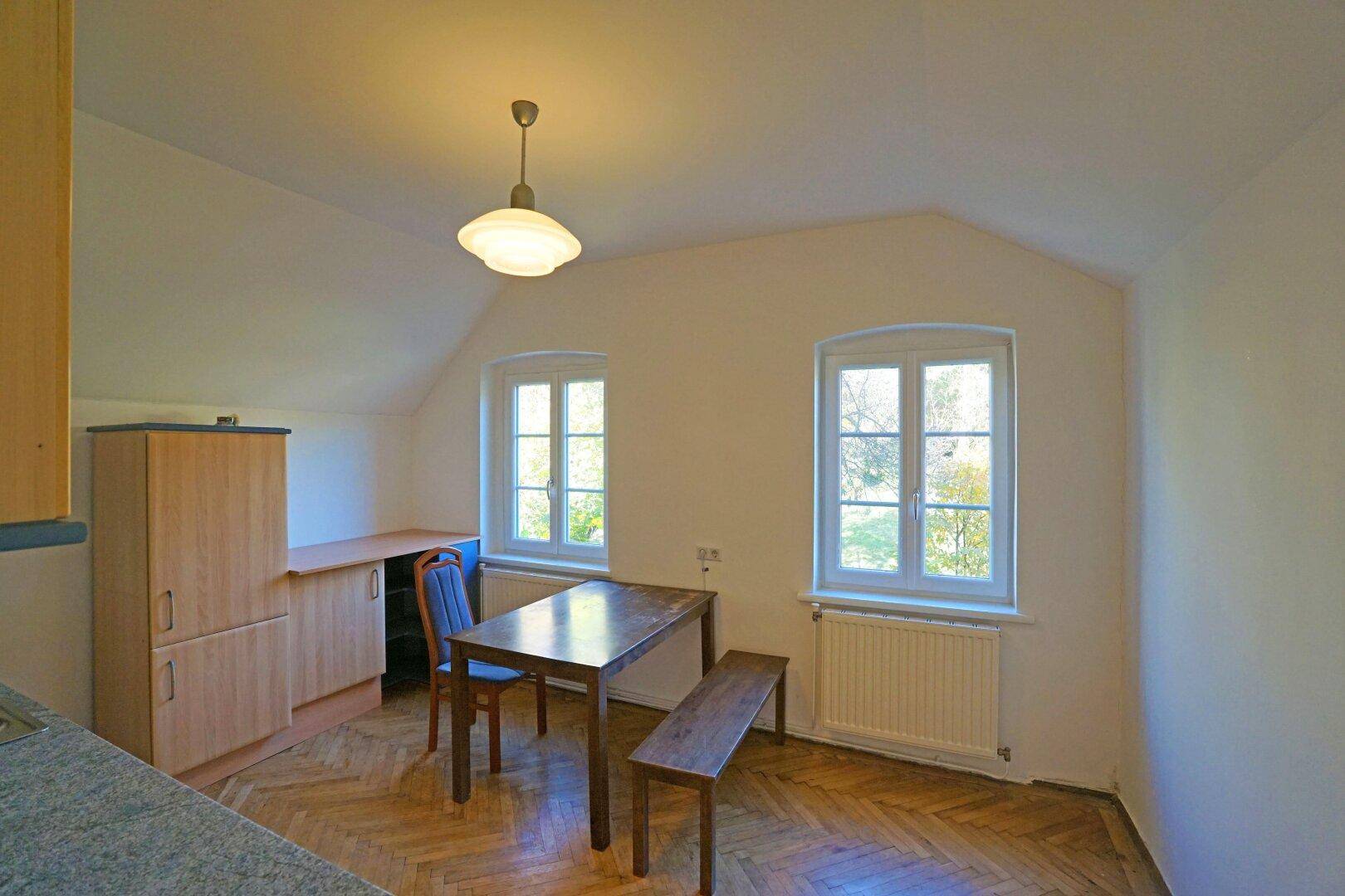 Helle Küche mit Essbereich, Holzschränken und Parkettboden im Dachgeschoss.