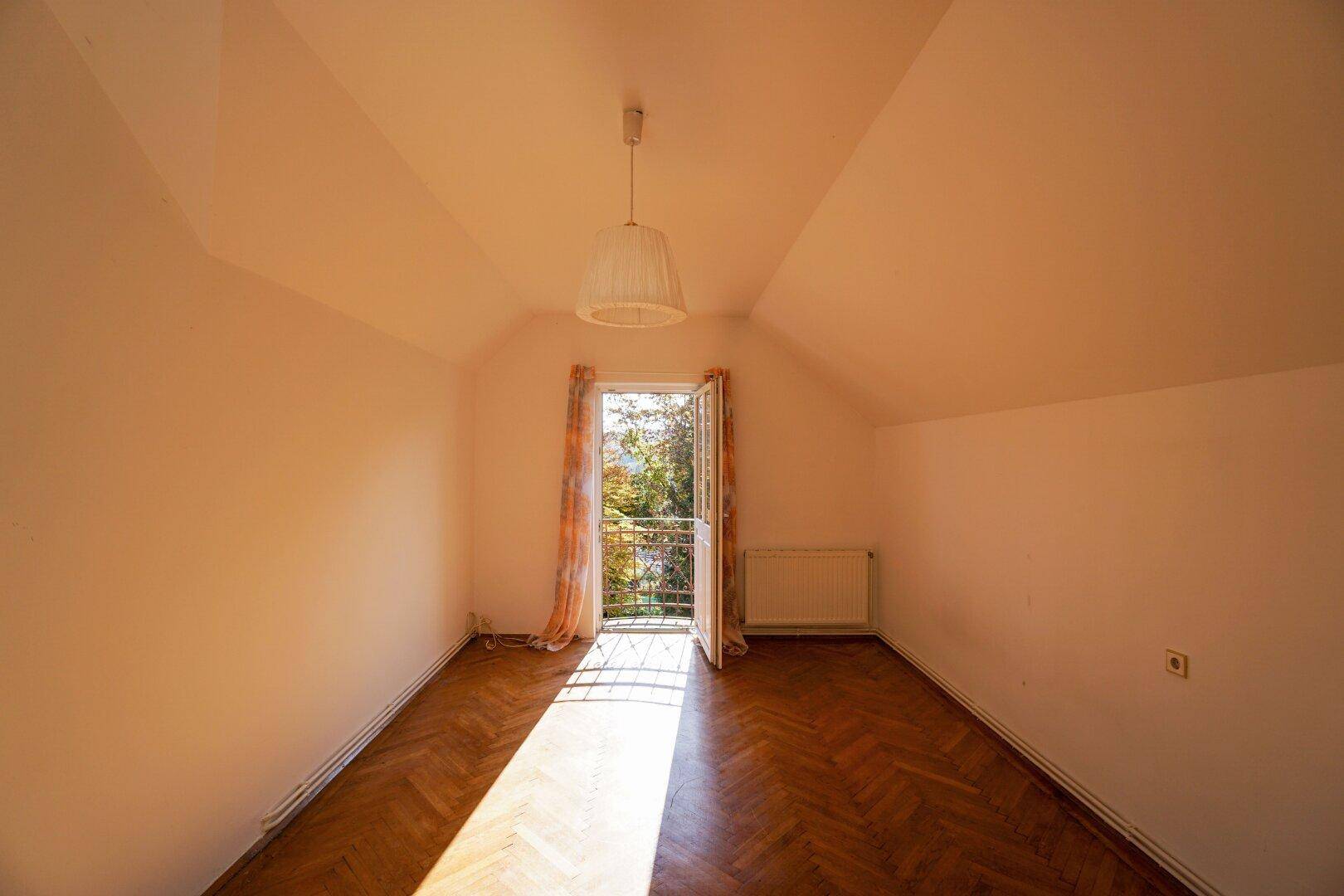 Helles Schlafzimmer im Dachgeschoss mit französischem Balkon und Parkettboden.