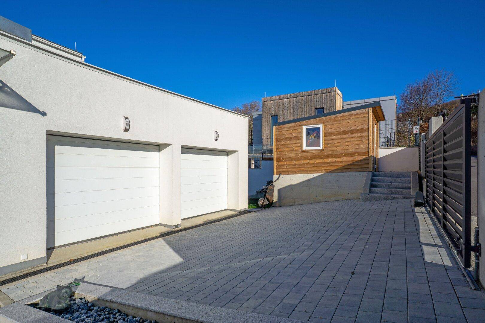 Doppelgarage mit Zufahrt und gepflastertem Bereich neben dem modernen Wohnhaus.