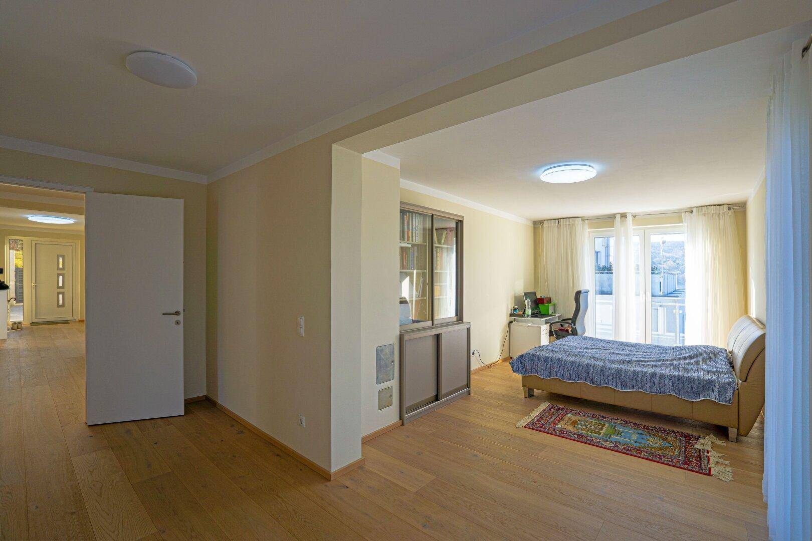 Helles Schlafzimmer mit Holzboden, Zugang zum Balkon und integriertem Stauraum.