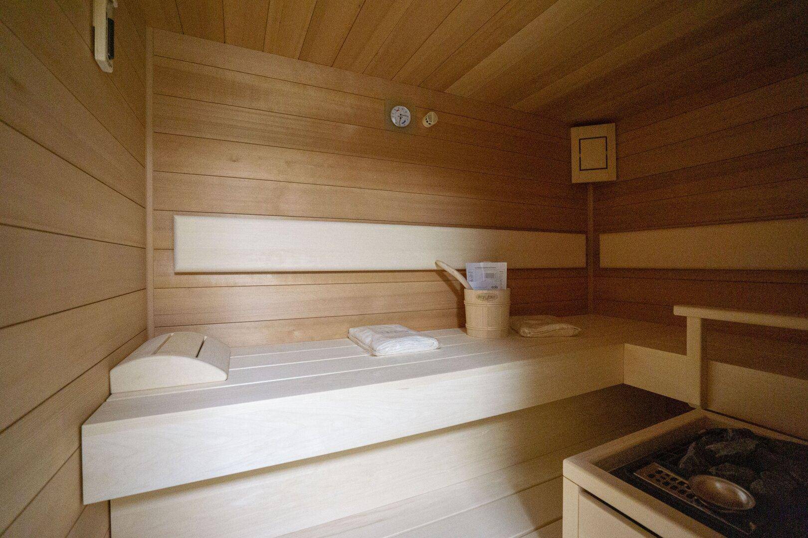 Gemütliche Holzsauna mit Bänken und traditionellem Saunaofen für Entspannung.