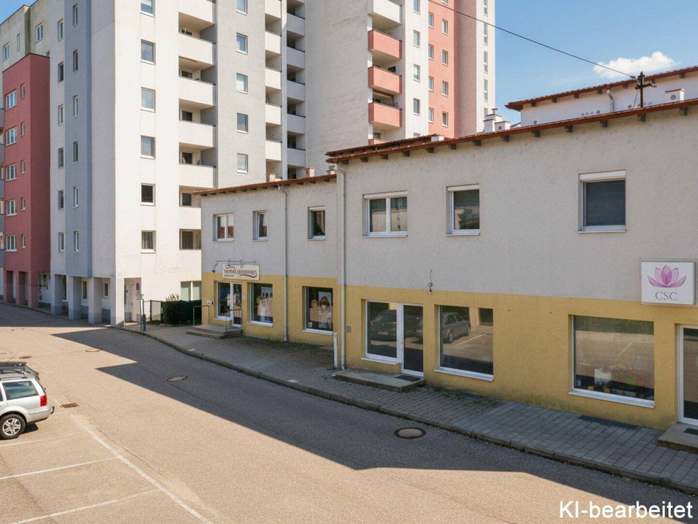 Gesamtansicht des Geschäftsgebäudes mit angrenzenden Wohnkomplexen und Parkplätzen in der Umgebung.