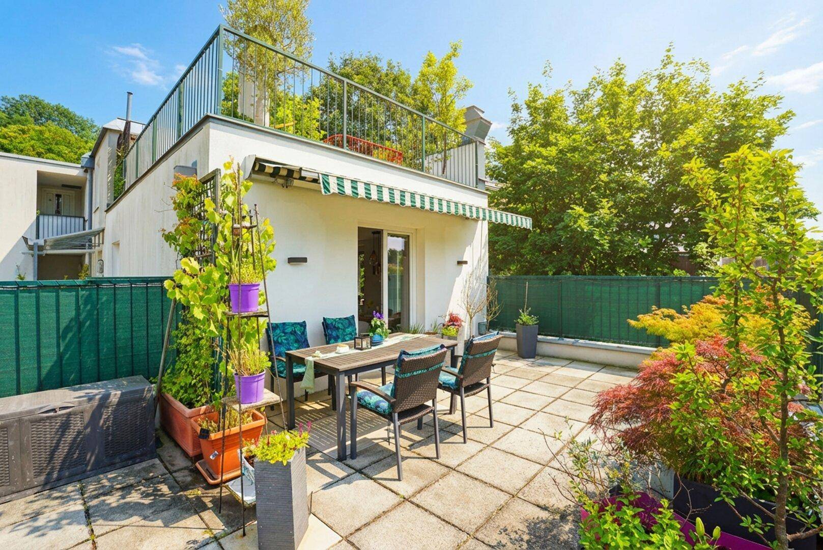 Sonniger Terrassenbereich mit Esstisch, Pflanzen und Blick auf die umliegende Natur.