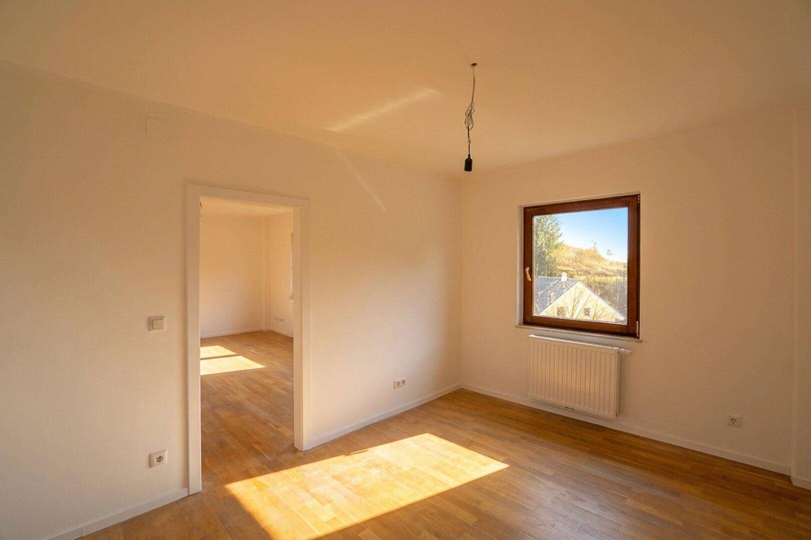 Helles Zimmer mit Laminatboden und einem Fenster, das einen schönen Ausblick bietet.