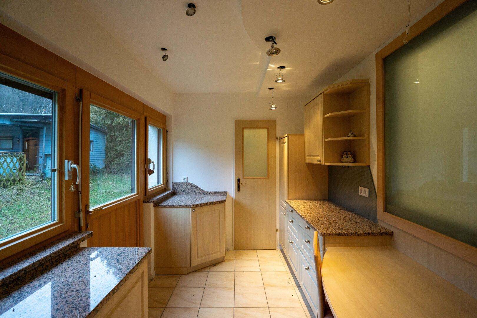Küche mit Granitarbeitsplatten und Zugang zum Garten, ideal für Mahlzeiten im Freien.