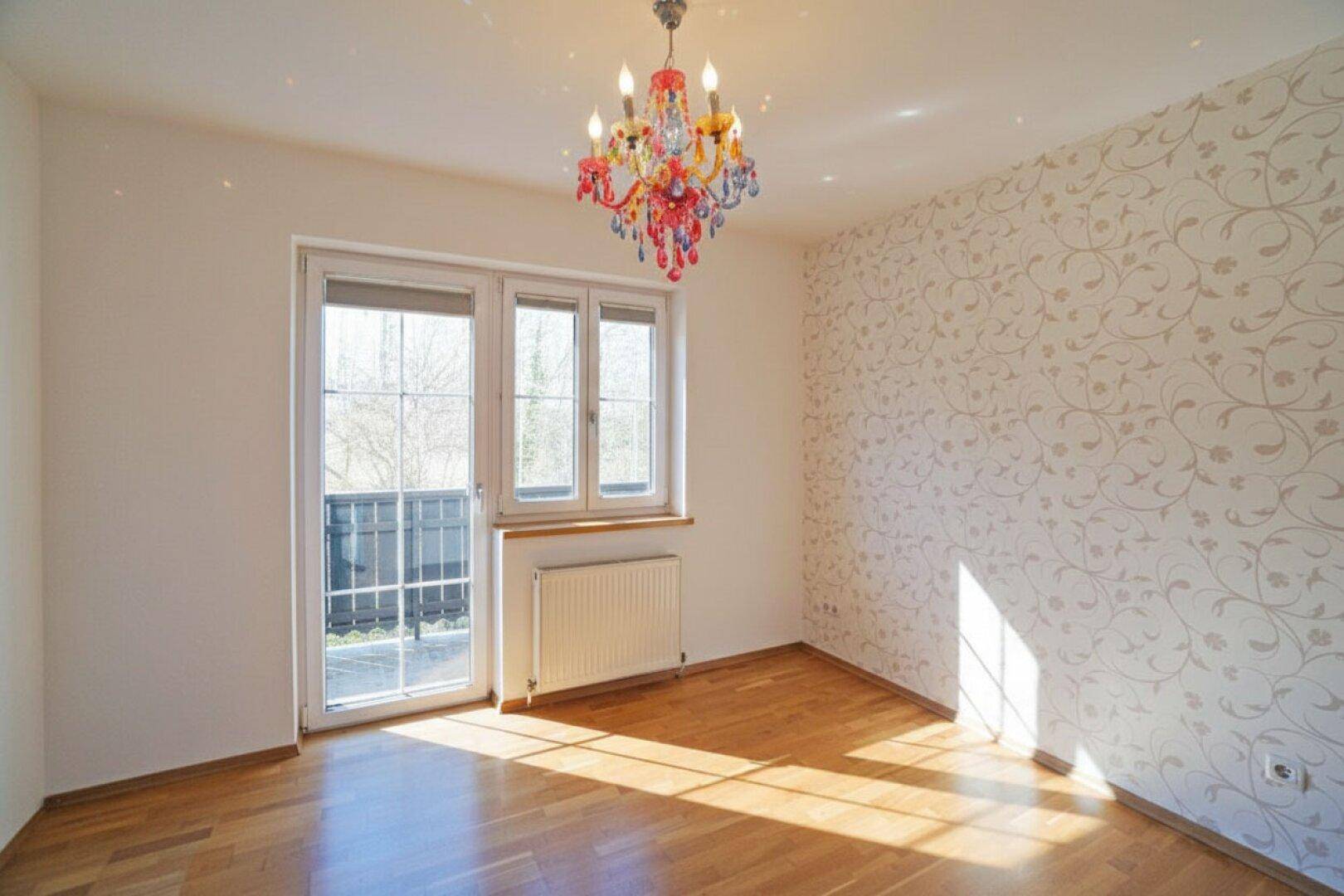 Helles Schlafzimmer mit Parkettboden, dekorativer Tapete und Zugang zum Balkon.